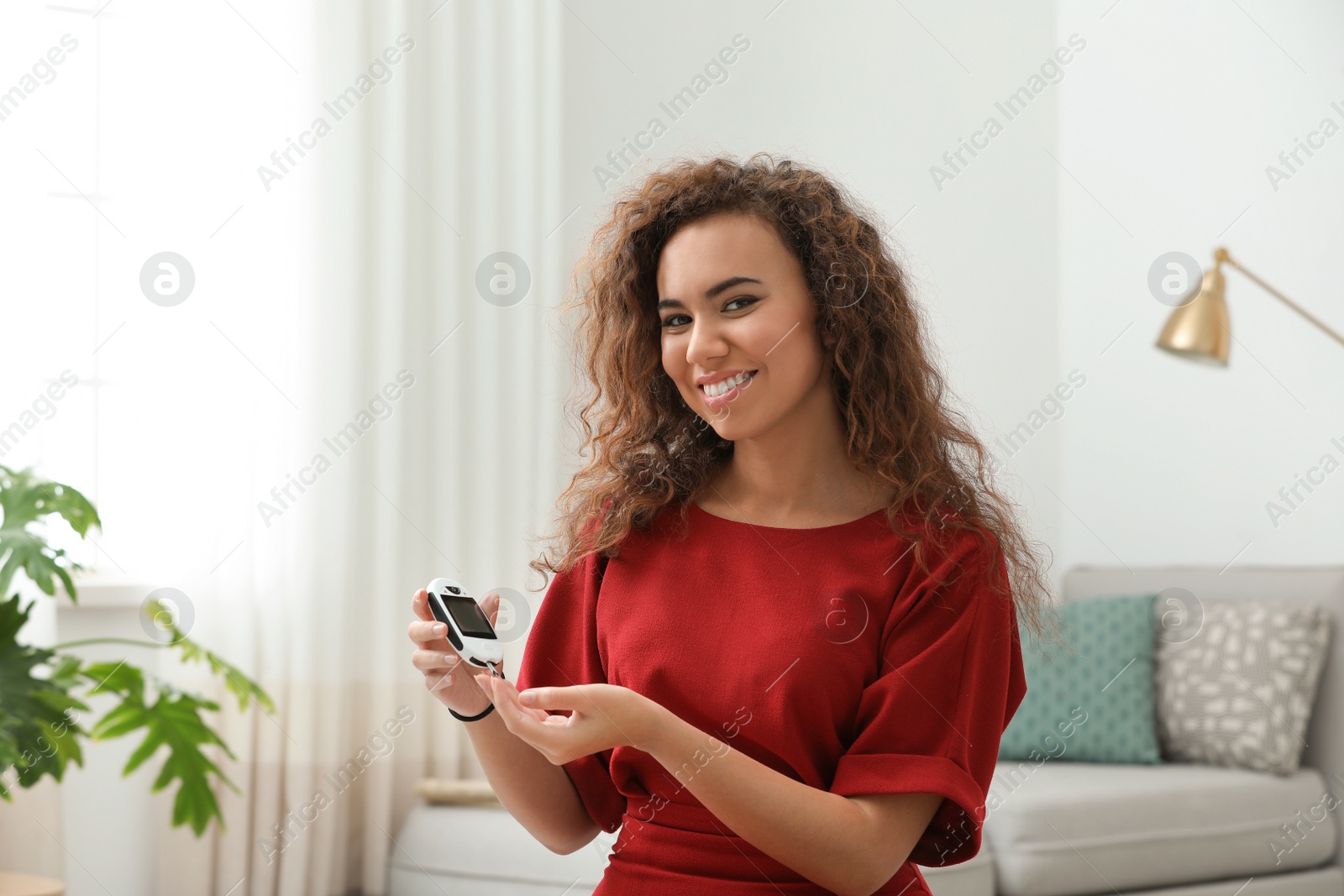 Photo of Young African-American woman using digital glucometer at home. Diabetes control