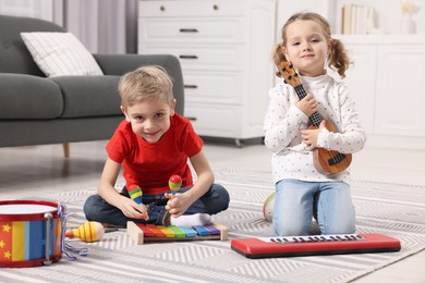 Little children playing toy musical instruments at home