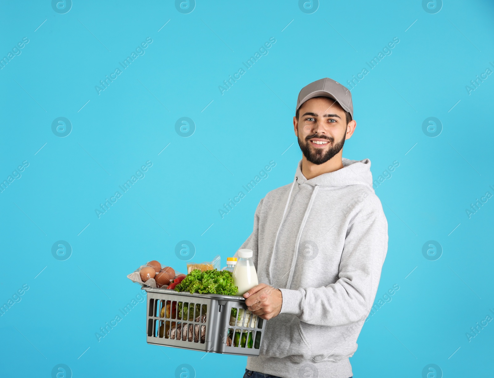 Photo of Man holding basket with fresh products on color background, space for text. Food delivery service