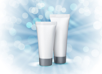 Tube of cosmetic product on light blue background with bokeh effect. Winter skin care