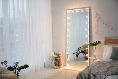 Large mirror with light bulbs in stylish room interior