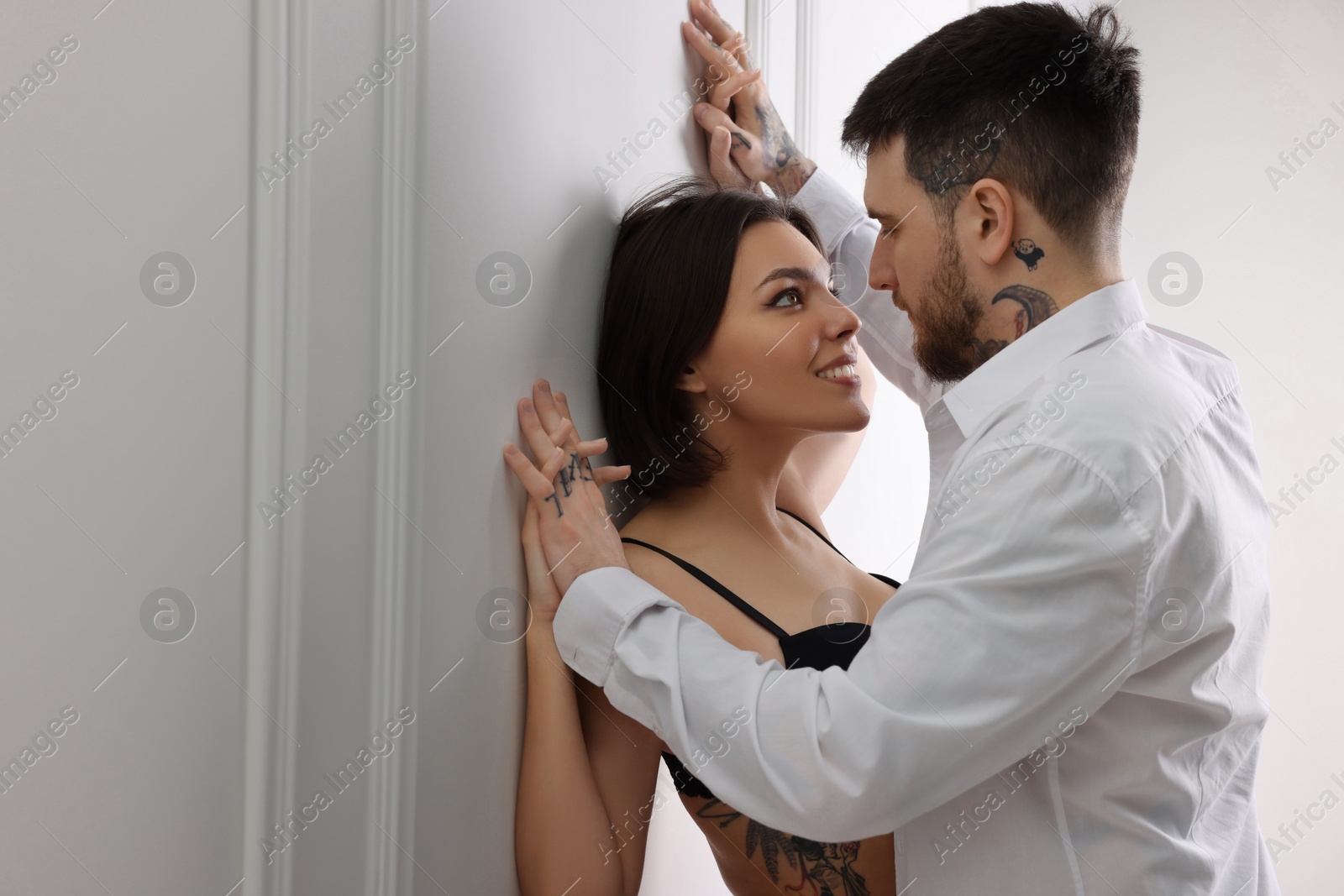 Photo of Passionate couple having sex near white wall indoors, space for text