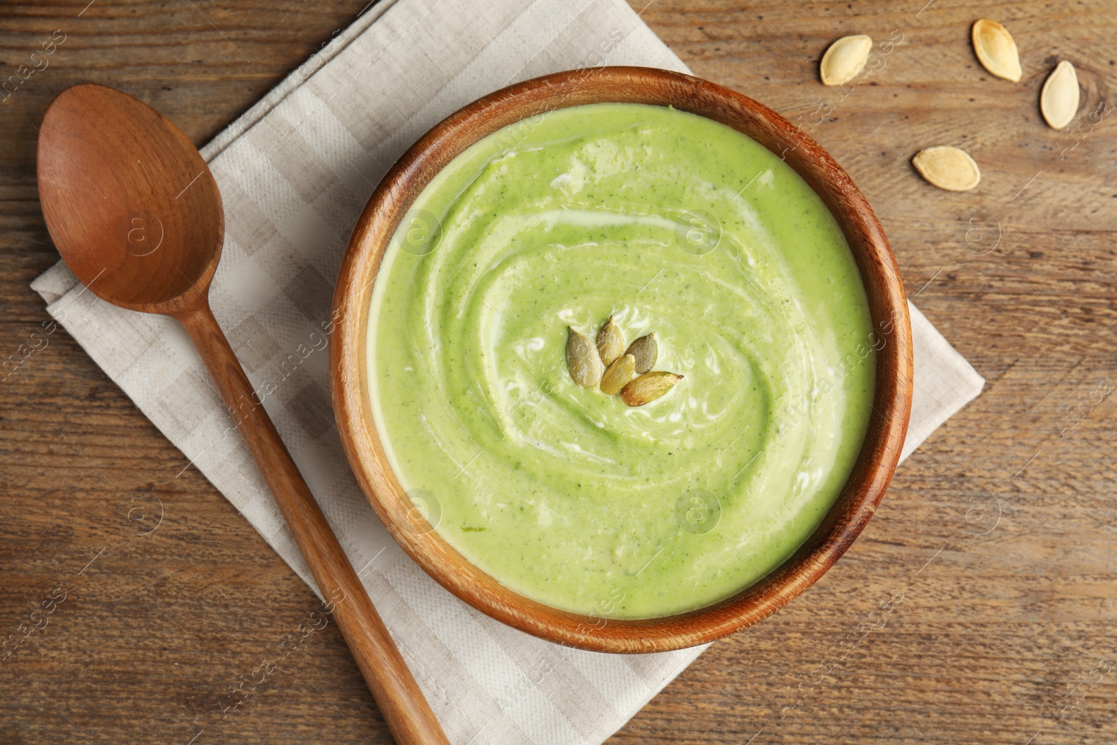 Photo of Delicious broccoli cream soup served on wooden table, flat lay