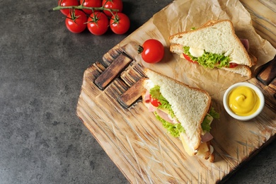 Photo of Tasty toast sandwiches served with mustard on wooden board. Wheat bread