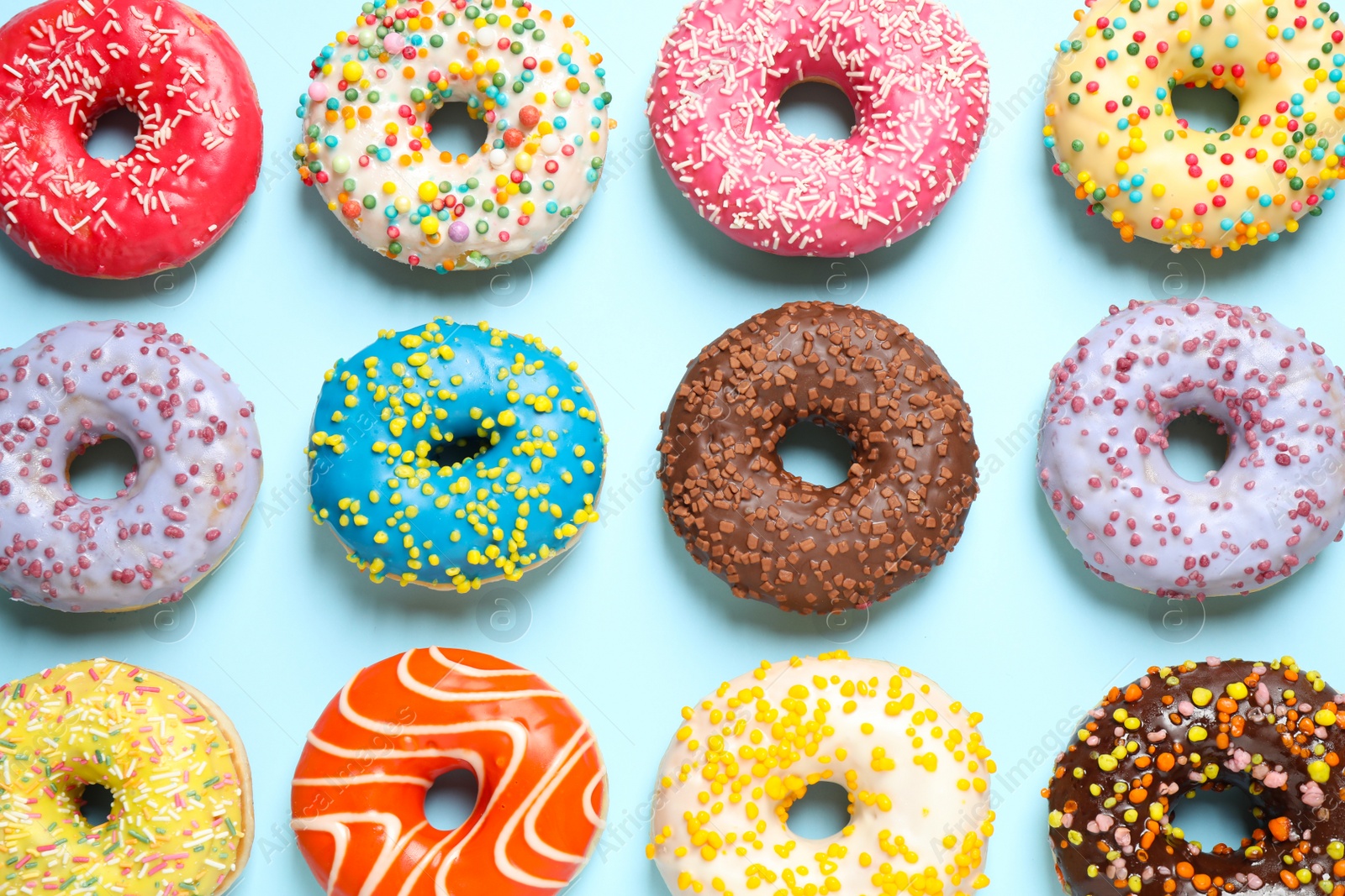 Photo of Delicious glazed donuts on light blue background, flat lay