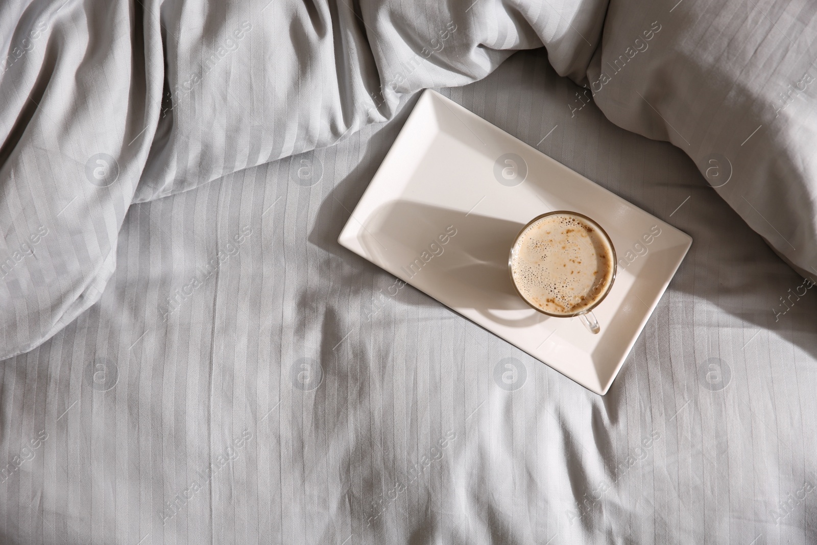 Photo of Tray with morning coffee on soft blanket, top view. Space for text