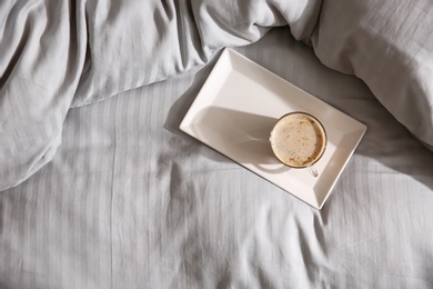 Tray with morning coffee on soft blanket, top view. Space for text