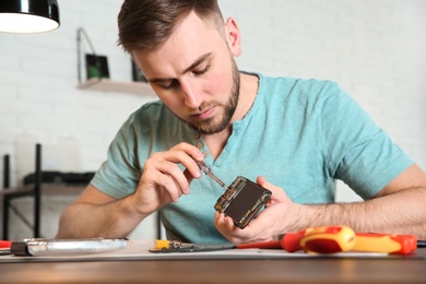 Photo of Technician repairing mobile phone at table in workshop