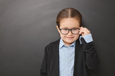 Happy little school child in uniform near chalkboard. Space for text