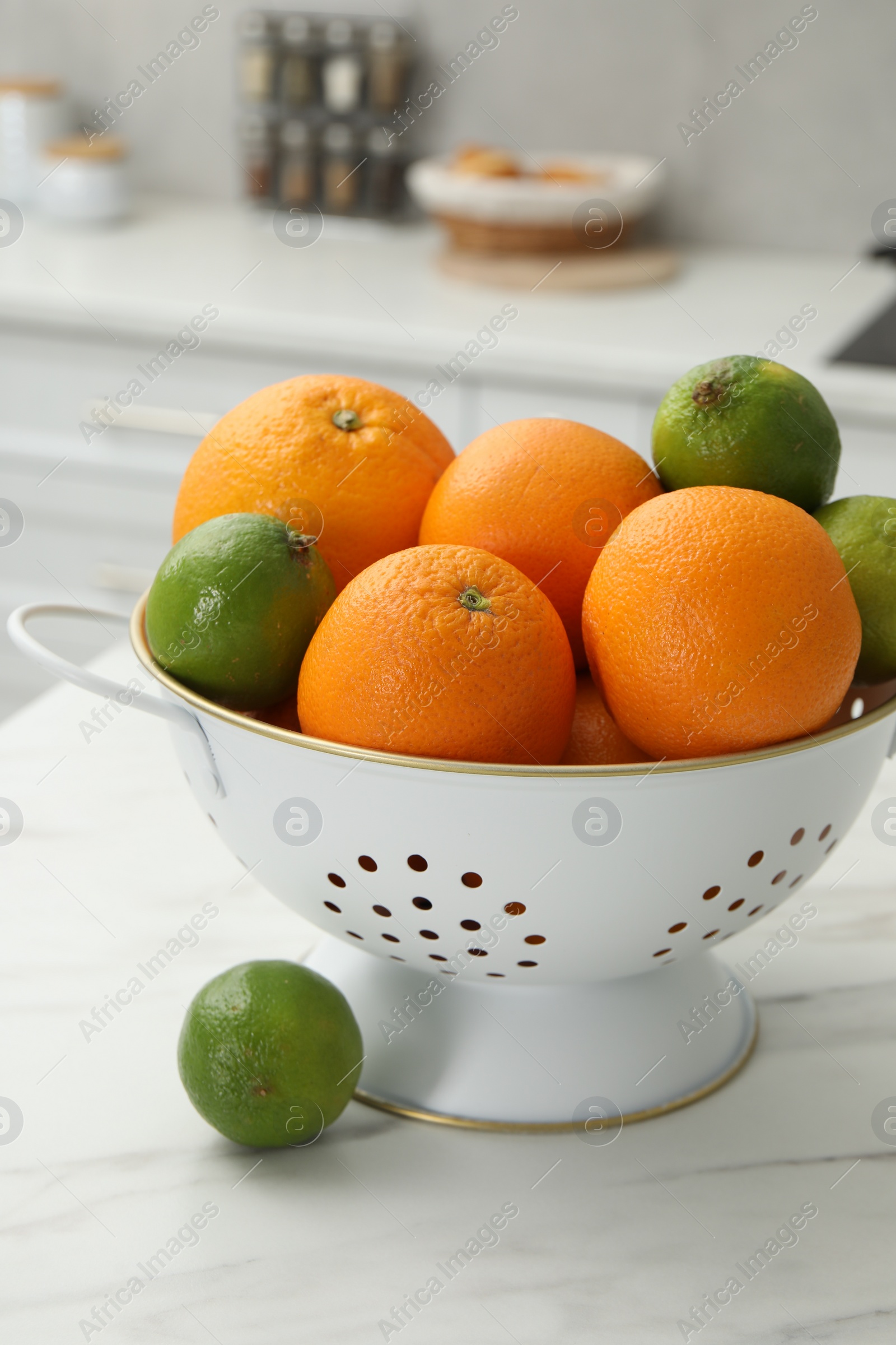 Photo of Colander with fresh fruits on white marble table in kitchen