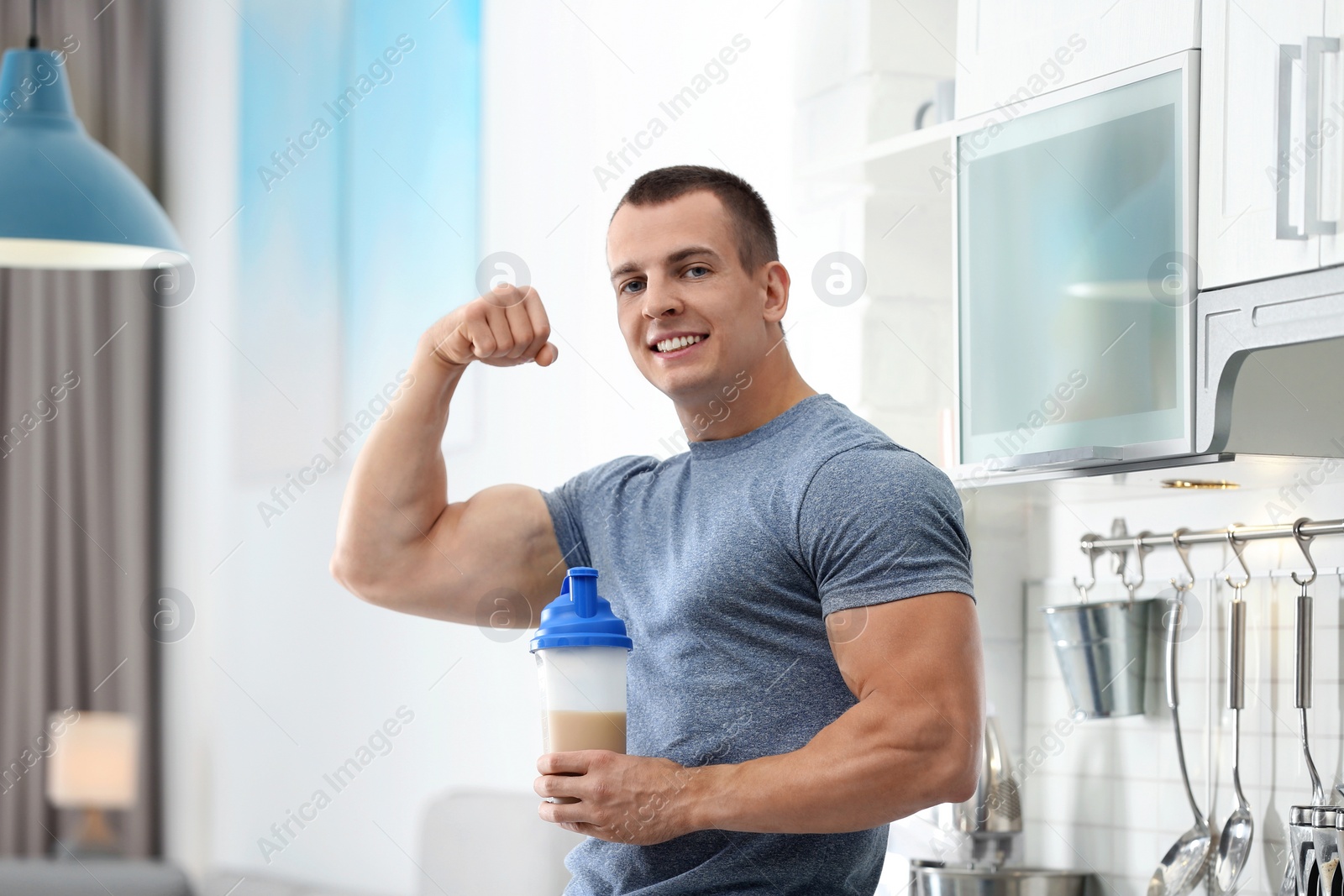 Photo of Athletic young man with protein shake in kitchen