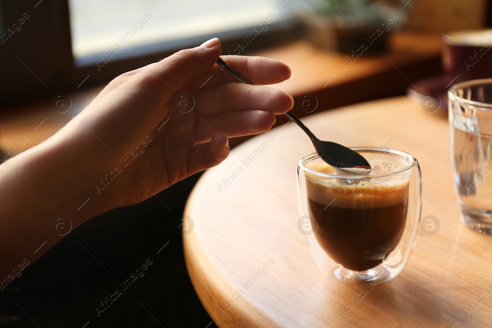 Photo of Woman with aromatic coffee at table in cafe, closeup