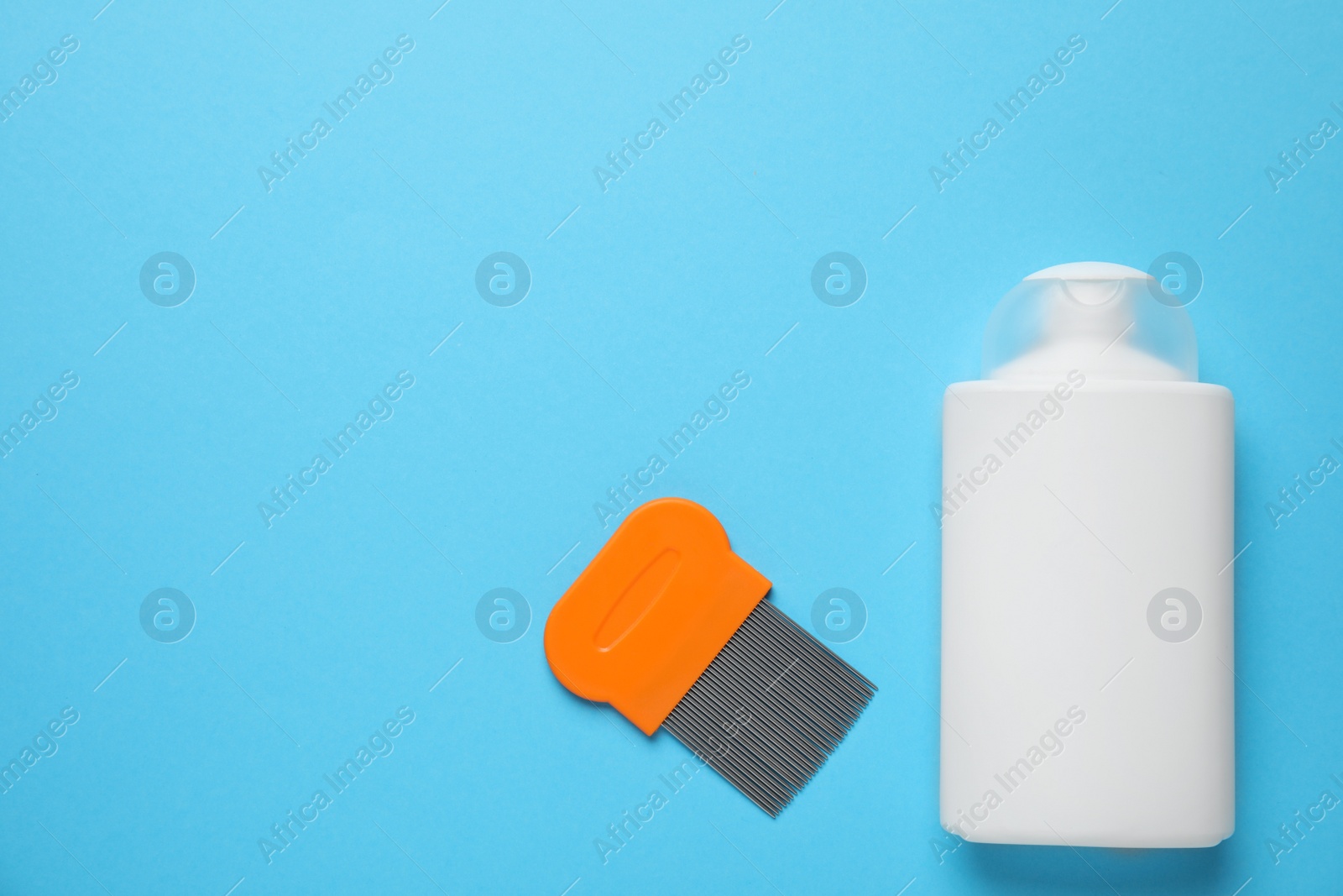 Photo of Shampoo and metal comb for anti lice treatment on light blue background, flat lay. Space for text