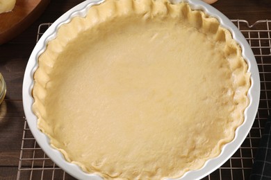 Photo of Pie tin with fresh dough and ingredients on wooden table., closeup Making quiche