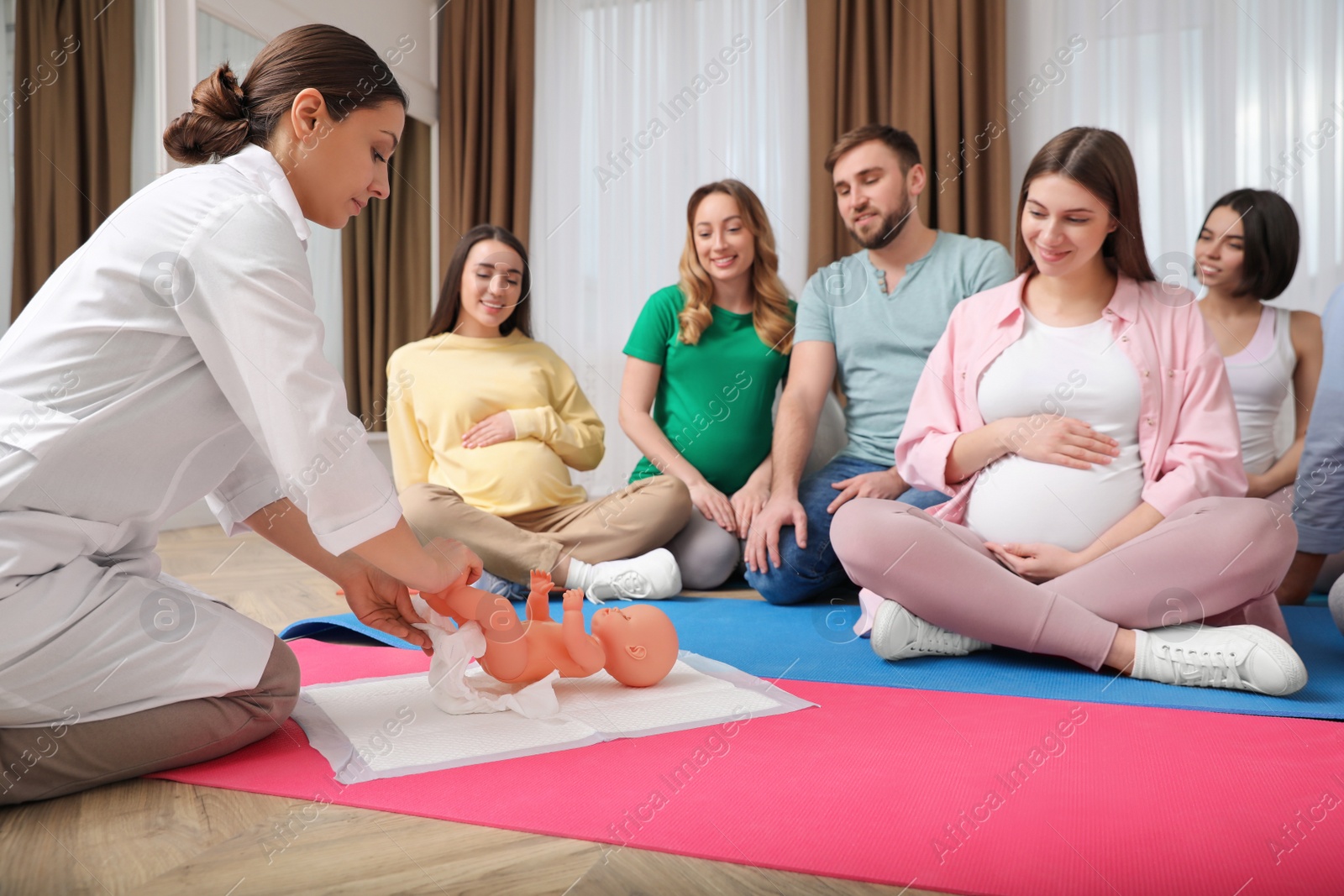 Photo of Group of pregnant women with men and doctor at courses for expectant parents indoors