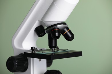 Modern microscope on green background, closeup. Medical equipment