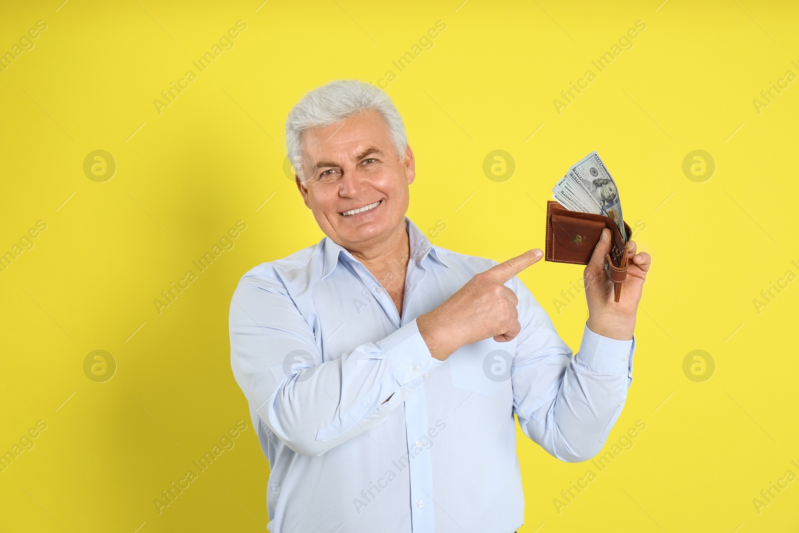 Photo of Happy senior man with cash money and wallet on yellow background