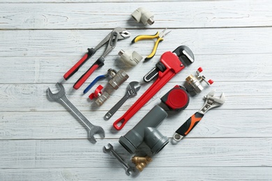 Photo of Flat lay composition with plumber's tools on white wooden background