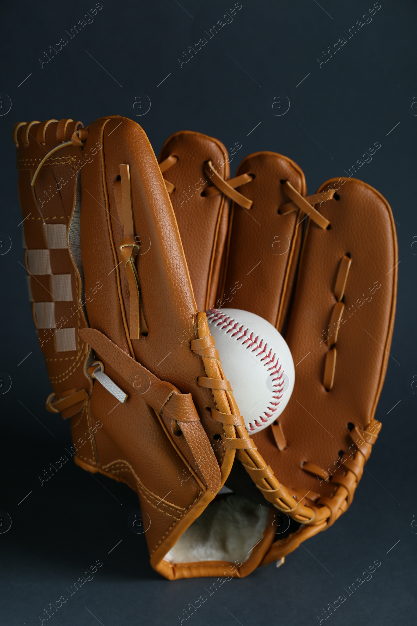 Photo of Catcher's mitt and baseball ball on dark background. Sports game