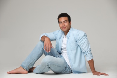 Photo of Handsome young African-American man sitting on light background