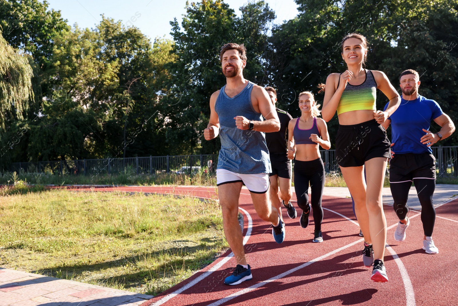 Photo of Group of people running at stadium on sunny day. Space for text