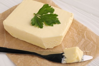 Tasty butter and knife on white wooden table, closeup