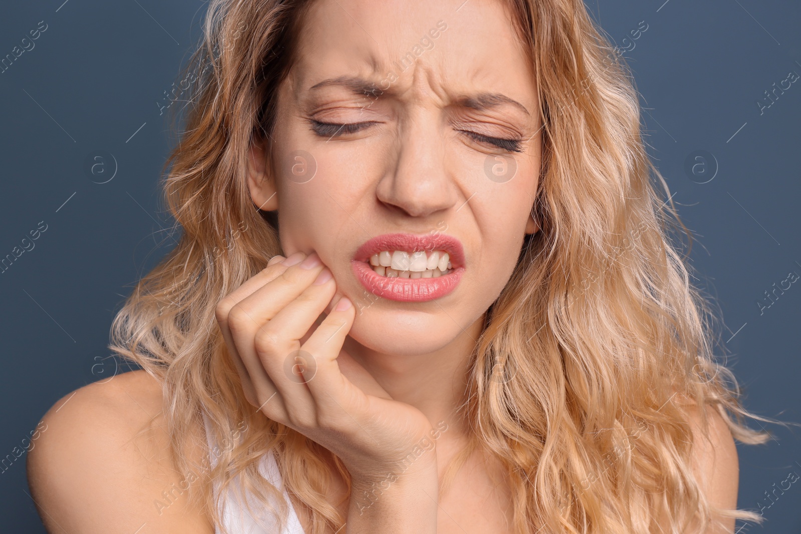 Photo of Young woman suffering from toothache on color background