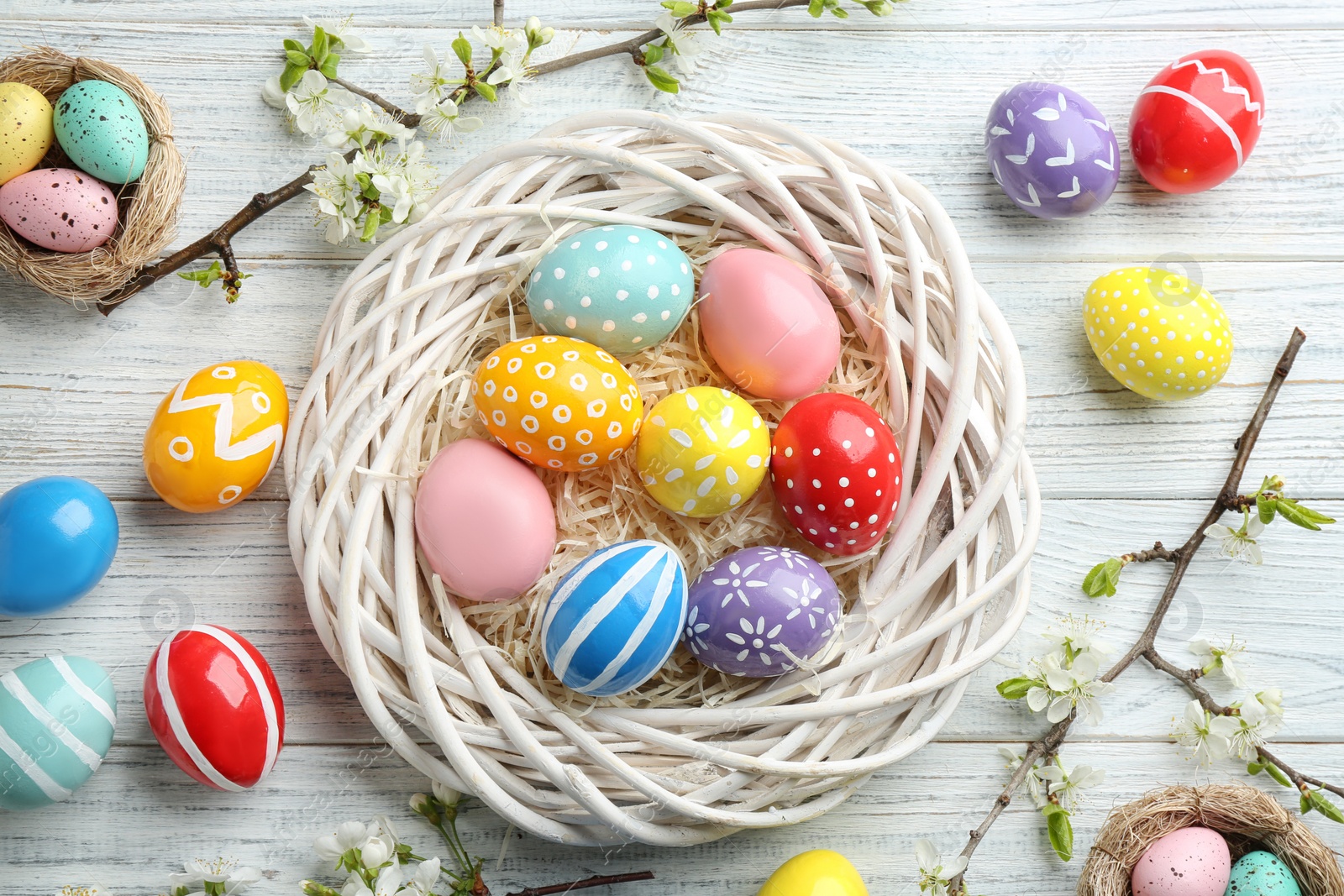 Photo of Flat lay composition with painted Easter eggs and blossoming branches on wooden background