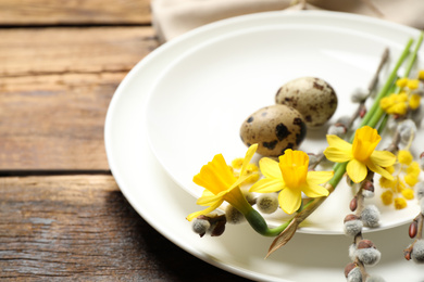 Photo of Festive Easter table setting with quail eggs and floral decor on wooden background, closeup