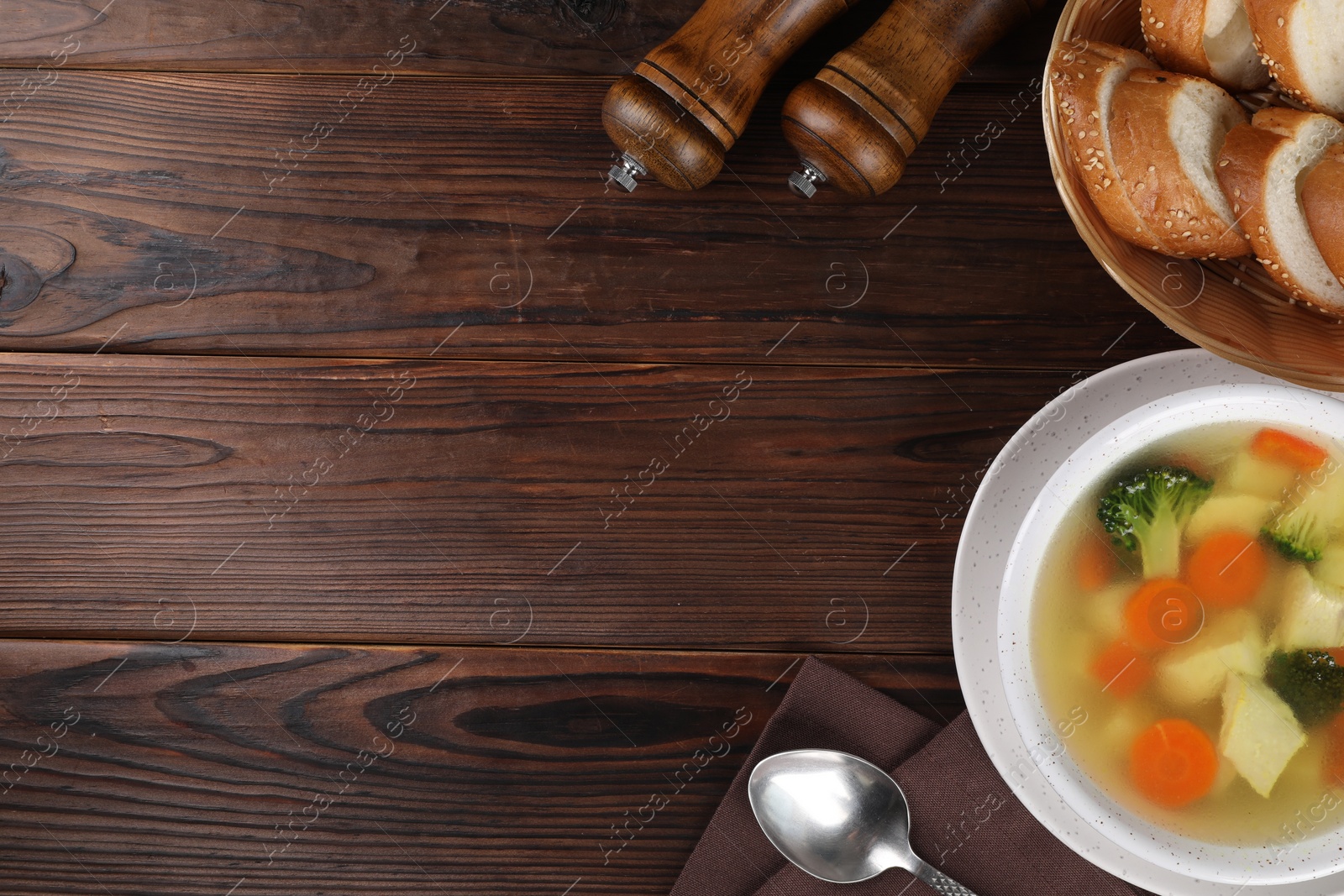 Photo of Tasty chicken soup with vegetables in bowl served on wooden table, flat lay. Space for text