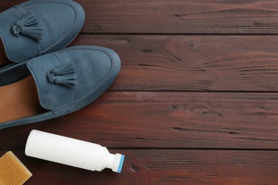 Stylish footwear with shoe care accessories on brown wooden table, flat lay. Space for text