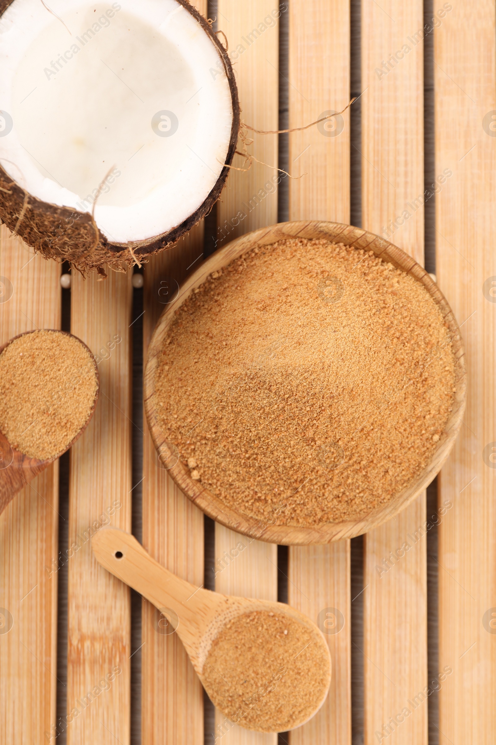 Photo of Coconut sugar, spoons, plate and fruit on wooden table, flat lay