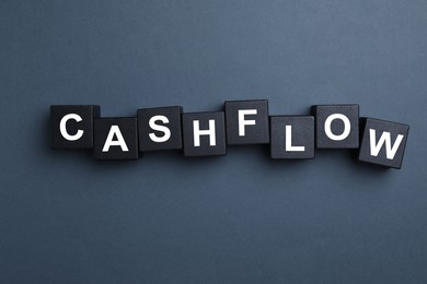 Image of Black wooden cubes with phrase Cash FLow on grey background, flat lay