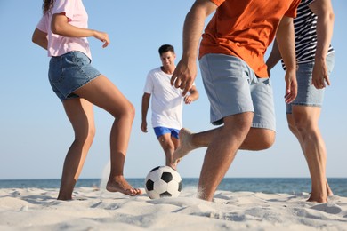 Photo of Group of friends playing football on beach, closeup