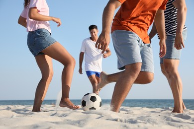 Group of friends playing football on beach, closeup