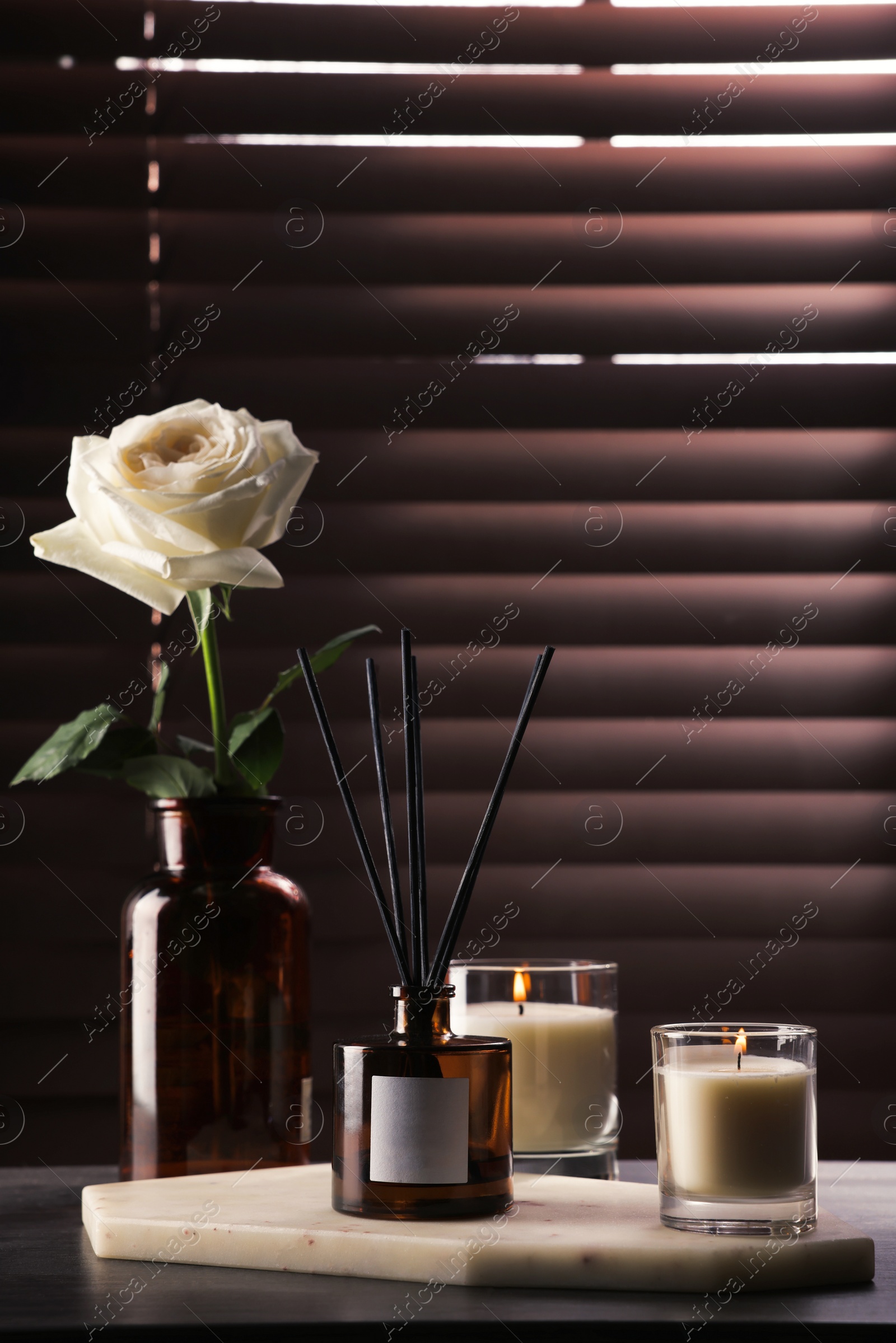 Photo of Aromatic reed air freshener and burning candles on windowsill