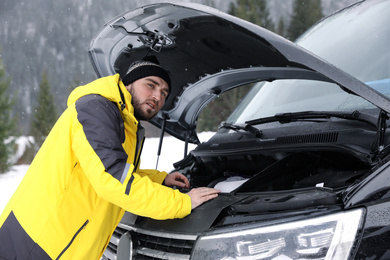 Photo of Stressed man near broken car outdoors on winter day