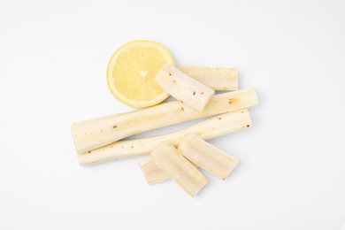 Photo of Cut raw salsify roots and lemon on white background, flat lay