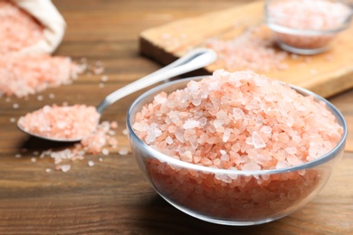 Photo of Pink himalayan salt in glass bowl on wooden table, closeup