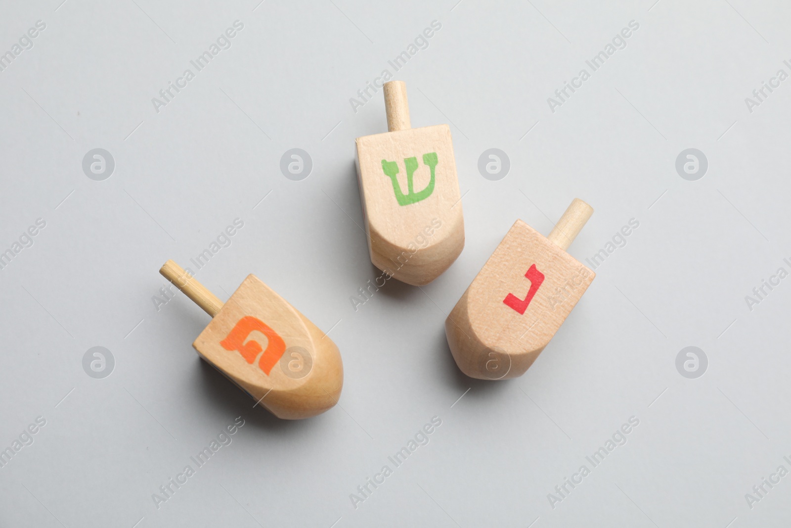 Photo of Wooden dreidels on light background, flat lay. Traditional Hanukkah game