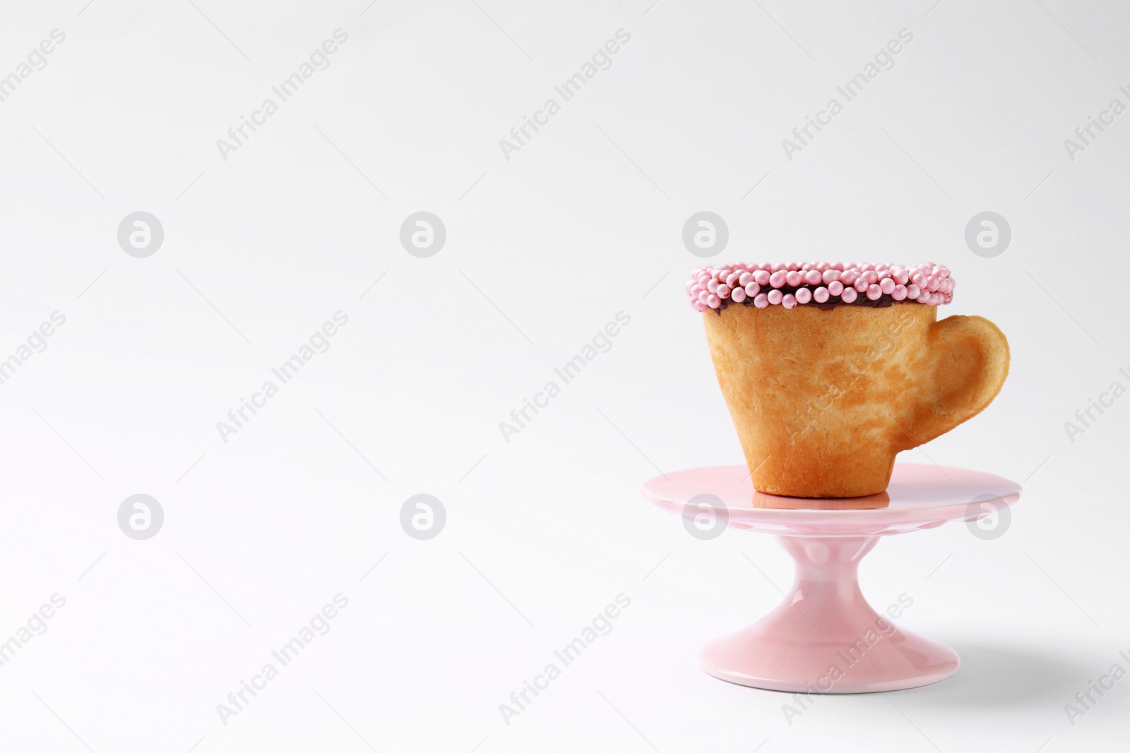 Photo of Delicious edible biscuit cup decorated with sprinkles on white background, space for text