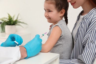 Photo of Children's hepatitis vaccination. Mother with her daughter in clinic. Doctor giving injection to little girl, closeup