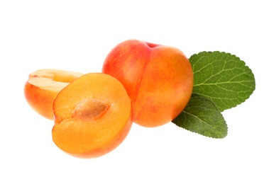 Whole and cut ripe plums with green leaves isolated on white, top view