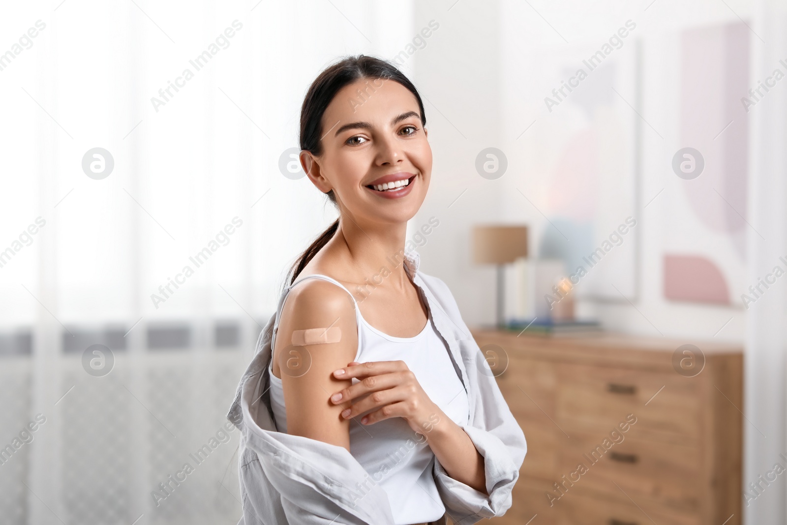 Photo of Woman with sticking plaster on arm after vaccination at home