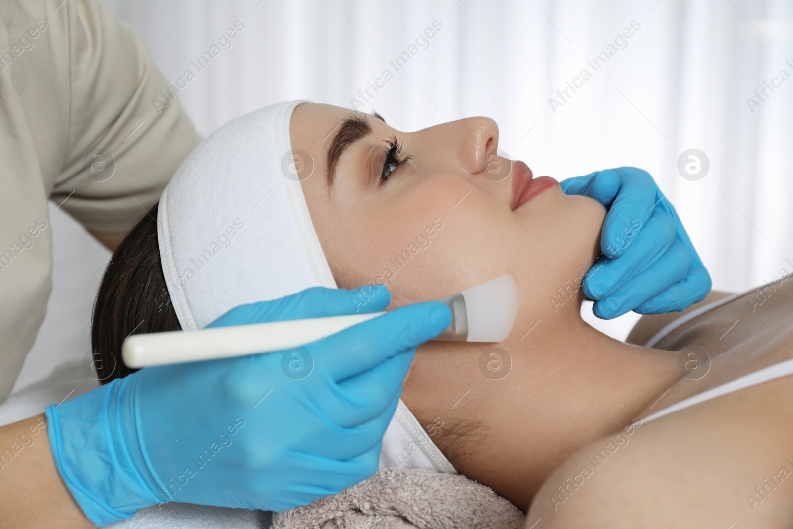 Photo of Young woman during face peeling procedure in salon