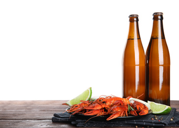 Delicious red boiled crayfishes and beer on wooden table against white background
