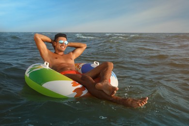 Photo of Man with inflatable ring resting in sea