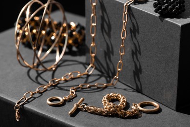 Photo of Presentation of metal chains and other different accessories on black table, closeup. Luxury jewelry