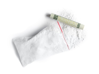 Photo of Cocaine in plastic bag and rolled money bill on white background, top view