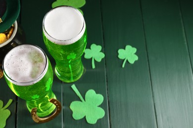Photo of St. Patrick's day party. Green beer, horseshoe and decorative clover leaves on wooden table. Space for text